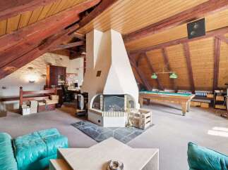 This stunning property boasts a unique and spacious interior with exposed wooden beams and a cozy fireplace.