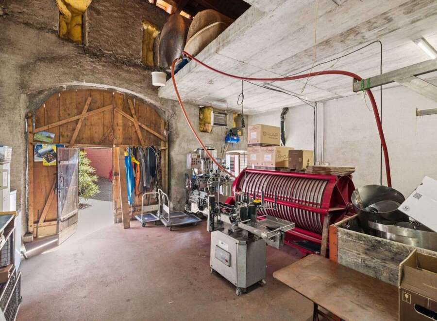 Discover the potential of this unique property! This space features a large wooden door, concrete walls, and industrial equipment, perfect for a workshop or creative studio.