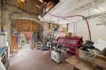 Discover the potential of this unique property! This space features a large wooden door, concrete walls, and industrial equipment, perfect for a workshop or creative studio.