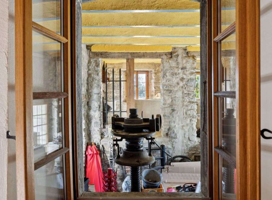 Step into a unique property with this captivating view! This image showcases a glimpse into a rustic interior, highlighting the charm of exposed stone walls and a vintage machine.