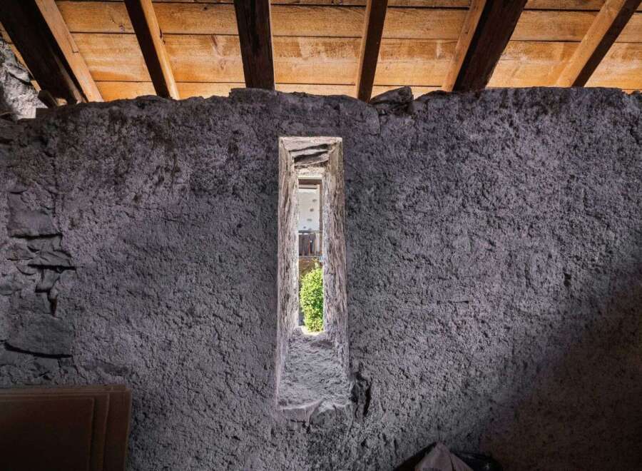 Discover the unique charm of this property, featuring exposed wooden beams and a rustic stone wall.
