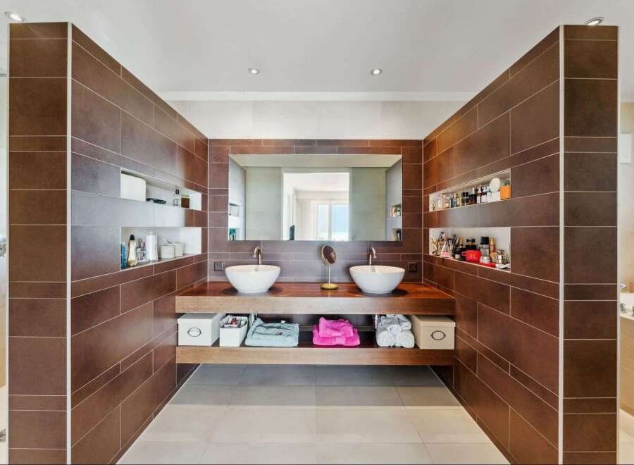 This luxurious bathroom features a modern design with sleek brown tiles and a double vanity.