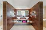 This luxurious bathroom features a modern design with sleek brown tiles and a double vanity.