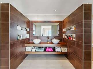 This luxurious bathroom features a modern design with sleek brown tiles and a double vanity.