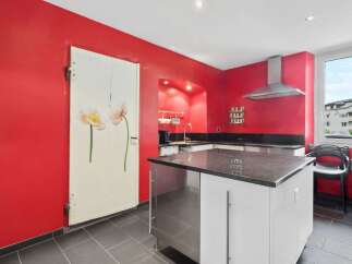 This stunning kitchen boasts a modern design with a striking red color scheme.