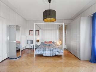 This spacious bedroom features a stylish four-poster bed with a cozy plaid comforter, creating a comfortable and inviting atmosphere.