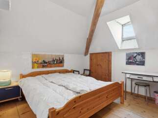 This charming bedroom features a cozy wooden bed frame and a bright, airy atmosphere.