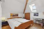 This charming bedroom features a cozy wooden bed frame and a bright, airy atmosphere.