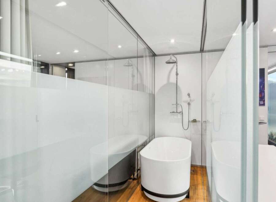 Experience luxury in this modern bathroom featuring a sleek, freestanding bathtub and a separate shower area.
