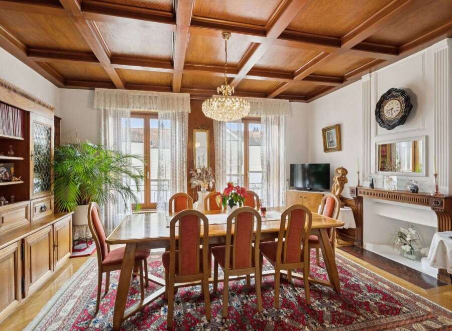 Step into luxury with this stunning dining room, featuring a beautiful wooden ceiling and elegant chandelier.
