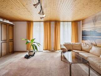 Step into this inviting living space, featuring a warm, wooden ceiling and ample natural light streaming through the large windows.