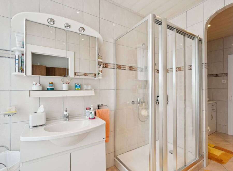 This bright and airy bathroom features a modern shower enclosure and a stylish vanity with ample storage.