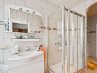 This bright and airy bathroom features a modern shower enclosure and a stylish vanity with ample storage.