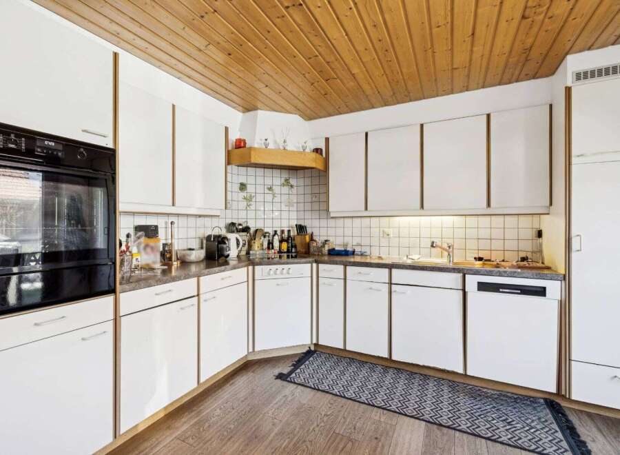 This charming kitchen boasts a warm, inviting atmosphere with its wooden ceiling and ample natural light.