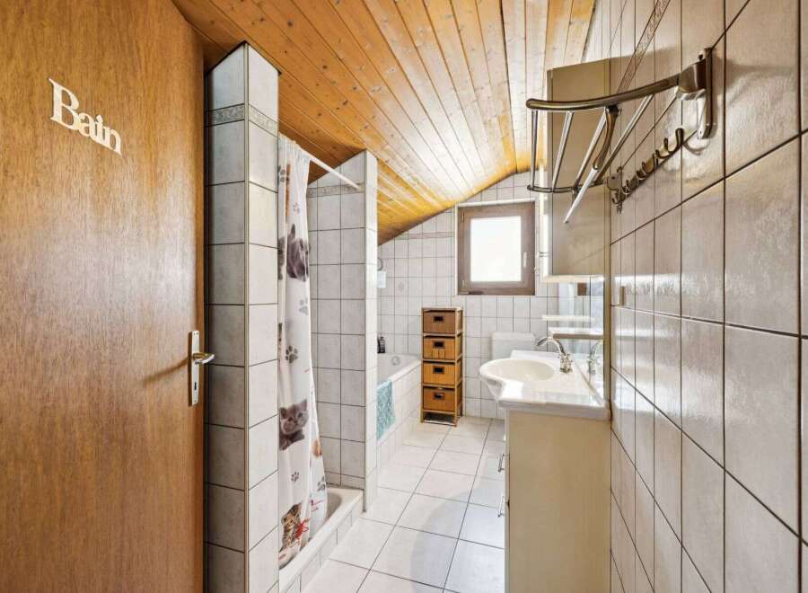 Step into this charming bathroom, featuring a unique sloped ceiling and a cozy atmosphere.