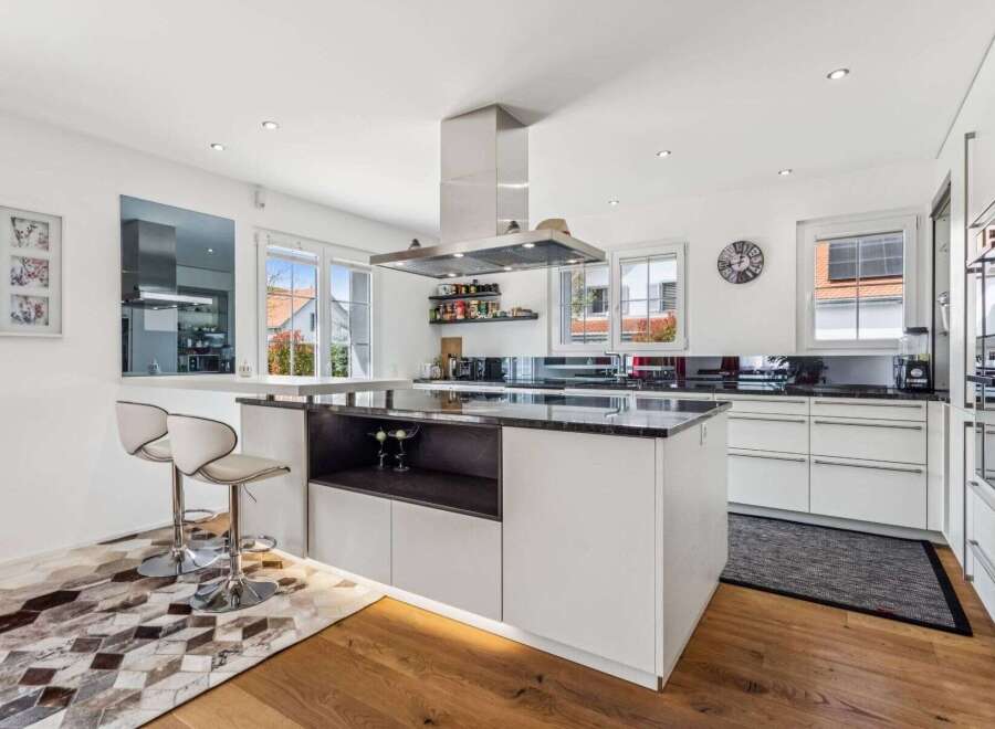 This stunning kitchen boasts a modern design with sleek white cabinetry and a contrasting dark countertop, creating a sophisticated and inviting atmosphere.