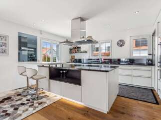 This stunning kitchen boasts a modern design with sleek white cabinetry and a contrasting dark countertop, creating a sophisticated and inviting atmosphere.