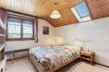 This charming bedroom features a cozy wooden ceiling and a skylight, creating a bright and airy atmosphere.