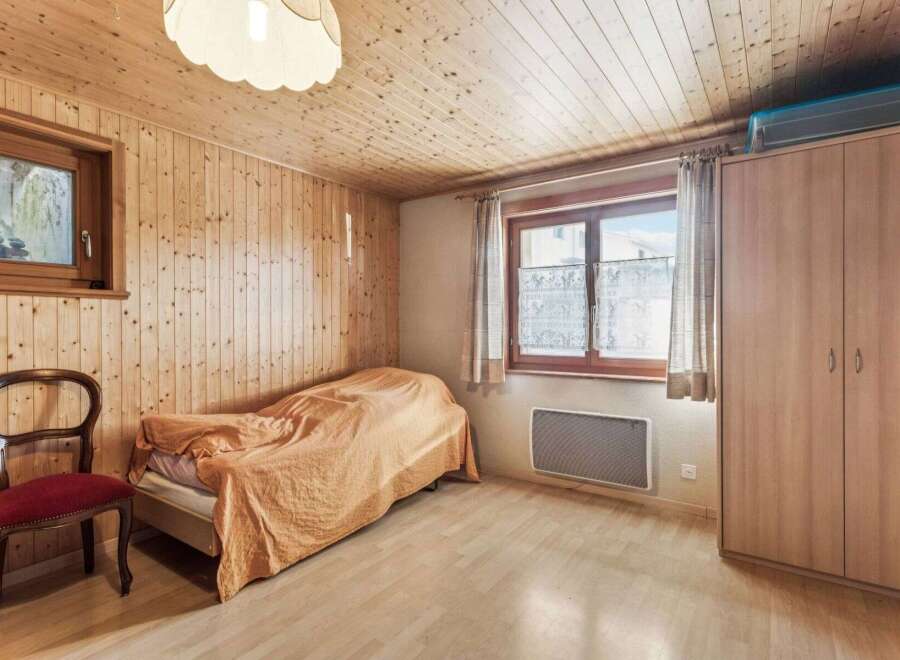 Cozy bedroom with wooden paneling and a comfortable bed.