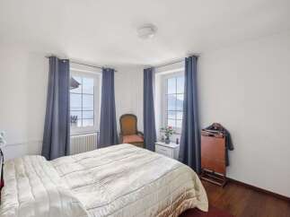 Experience serene living in this charming bedroom, featuring stunning views from its windows.