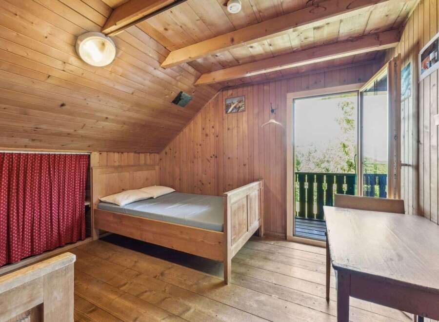 This charming cabin bedroom offers a cozy retreat with its wooden interior and natural light.