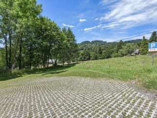 Discover this stunning property featuring a unique parking area with a grass-filled grid, blending seamlessly with the natural landscape.