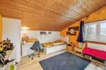 This charming bedroom features a cozy, sloped wooden ceiling and a vibrant orange accent wall.