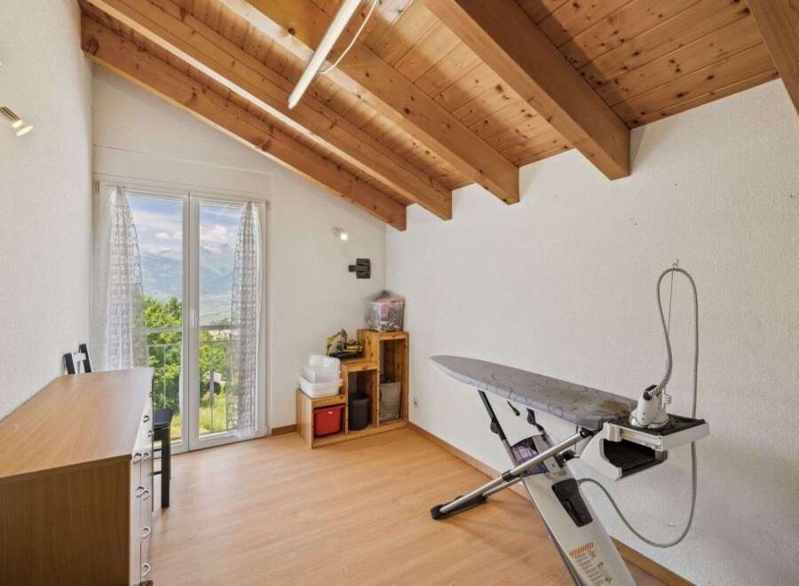 This charming property boasts a bright and airy interior with a unique sloped ceiling and exposed wooden beams.