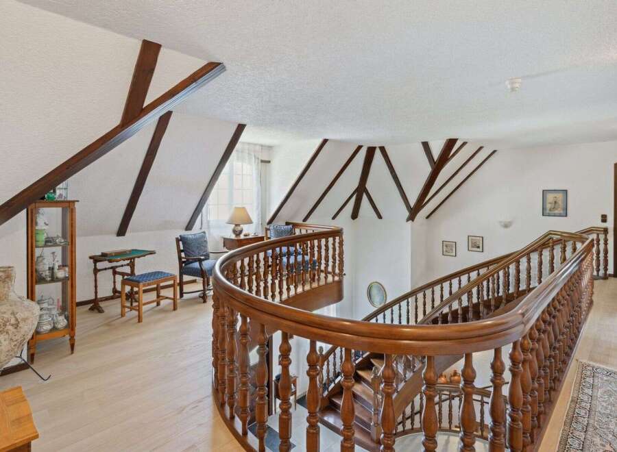 Step into luxury with this stunning property featuring a grand staircase and elegant wooden accents.