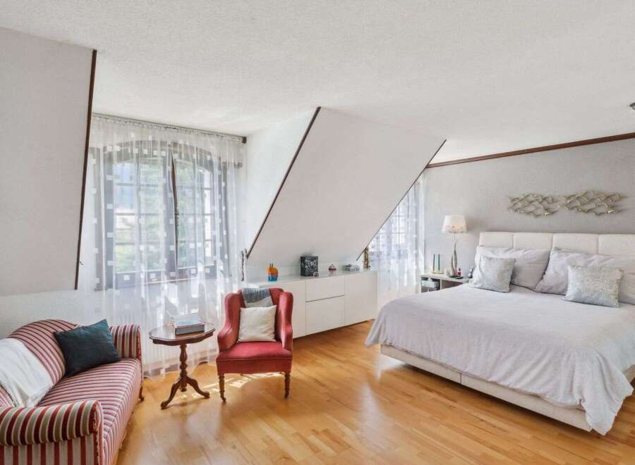 This stunning bedroom boasts a unique architectural design with a slanted ceiling, creating a modern and airy feel.