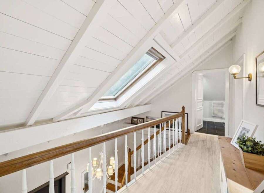 Discover the charm of this stunning property, featuring a beautifully designed hallway with a unique sloped ceiling and a skylight that floods the space with natural light.