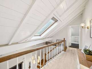 Discover the charm of this stunning property, featuring a beautifully designed hallway with a unique sloped ceiling and a skylight that floods the space with natural light.