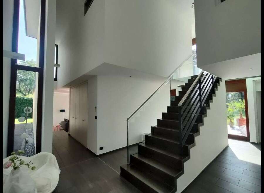 Step into luxury with this stunning modern home! Featuring a grand staircase with sleek black railings and glass accents, this property exudes elegance.