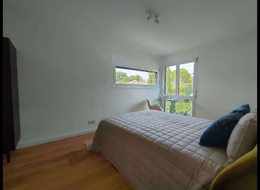 This bright and airy bedroom offers a serene retreat with its neutral color palette and ample natural light.