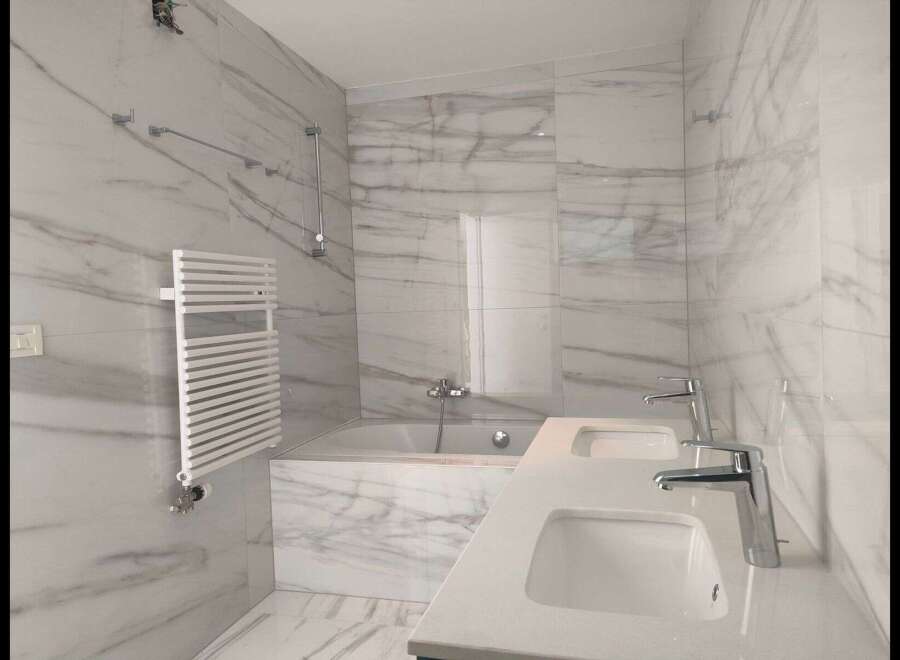 This luxurious bathroom boasts a modern design with stunning marble-like tiles, creating a spa-like ambiance.