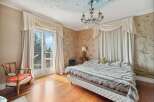 Step into luxury with this exquisite bedroom, featuring a stunning chandelier and elegant curtains.