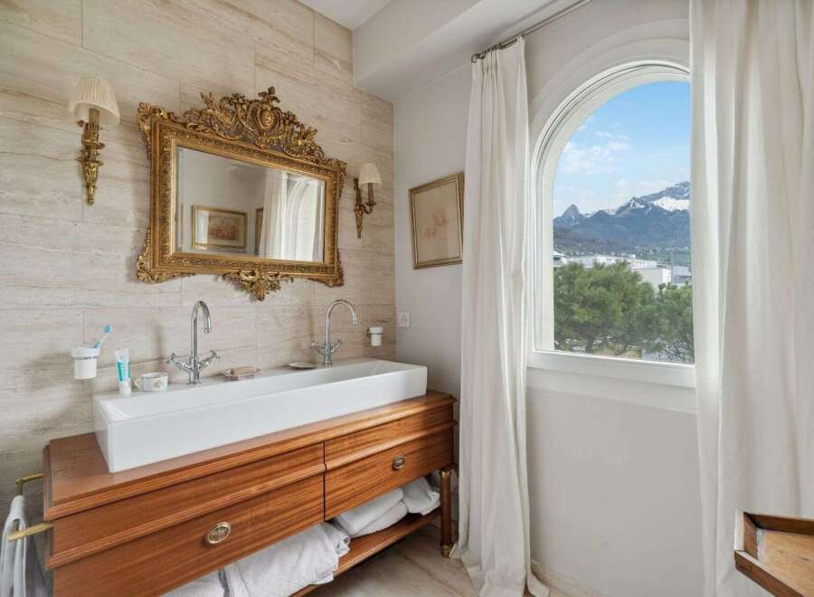 Experience luxury in this exquisite bathroom featuring a stunning gold-framed mirror and a sleek, modern sink.