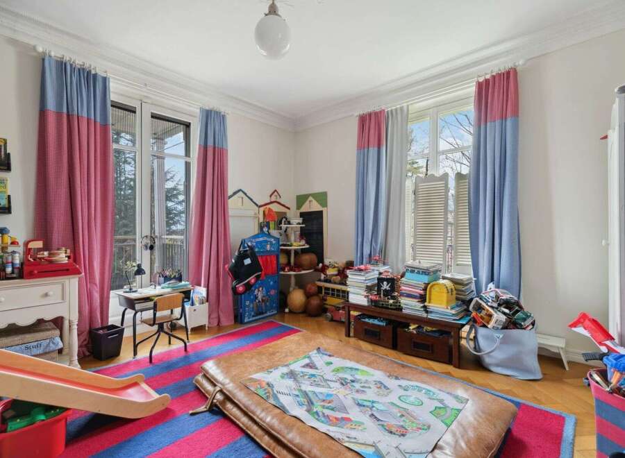 This charming children's room features a playful design with colorful curtains and a vibrant striped rug.