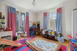 This charming children's room features a playful design with colorful curtains and a vibrant striped rug.