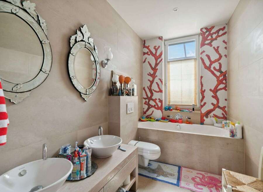 This stunning bathroom boasts a unique design with coral-inspired mosaic tiles and elegant decorative mirrors.