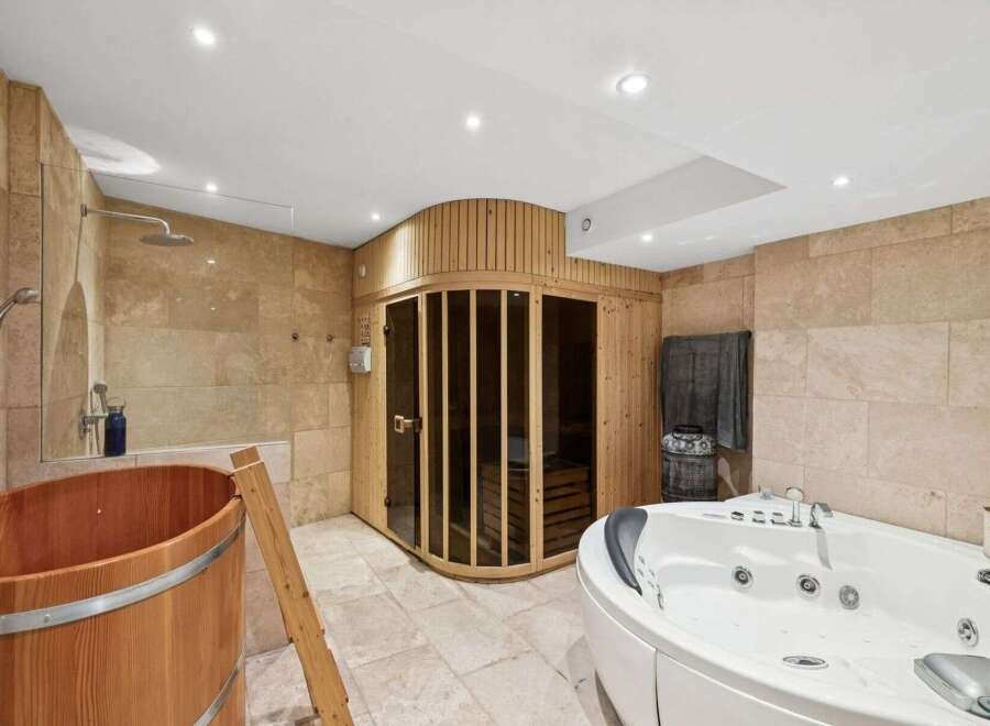 Indulge in luxury with this spa-like bathroom featuring a sauna, a jacuzzi, and a wooden tub.