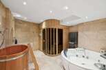 Indulge in luxury with this spa-like bathroom featuring a sauna, a jacuzzi, and a wooden tub.