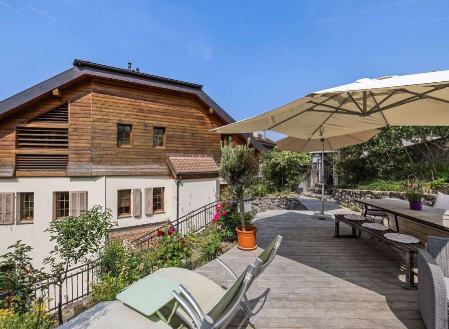 Enjoy the tranquility of this stunning property featuring a spacious wooden deck, perfect for outdoor gatherings.
