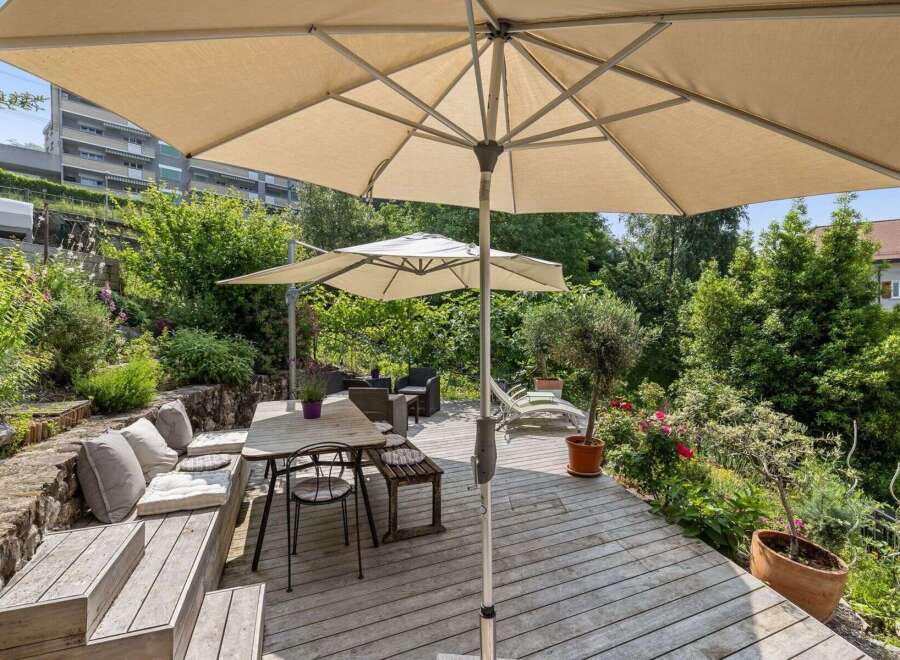 Enjoy outdoor living at its finest with this stunning property featuring a spacious wooden deck and lush greenery.