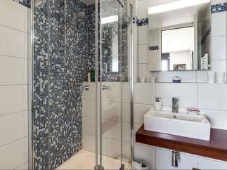 Step into a modern bathroom oasis! This stunning space features a sleek glass shower enclosure with a mosaic tile accent wall, creating a spa-like atmosphere.