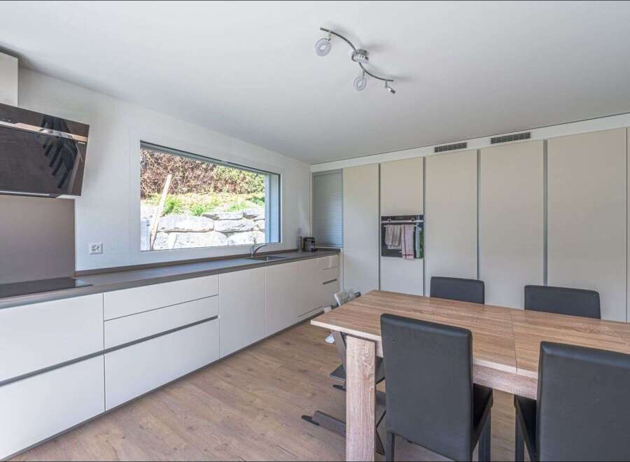This modern kitchen boasts sleek cabinetry and a spacious layout, perfect for culinary enthusiasts.