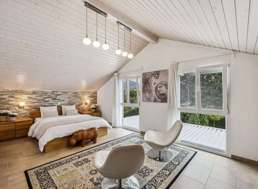 This stunning bedroom boasts a unique design with a vaulted ceiling and exposed wooden beams, creating a spacious and airy atmosphere.