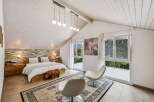 This stunning bedroom boasts a unique design with a vaulted ceiling and exposed wooden beams, creating a spacious and airy atmosphere.