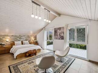 This stunning bedroom boasts a unique design with a vaulted ceiling and exposed wooden beams, creating a spacious and airy atmosphere.