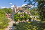 Discover the charm of this stunning property, showcasing a beautiful stone facade and a lush, green landscape.